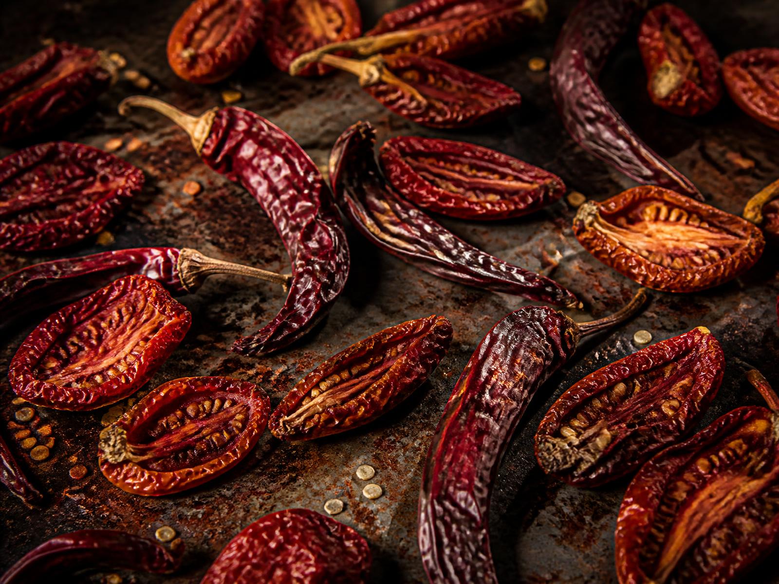 Dried red peppers and dried tomato halves on an industrial steel tray