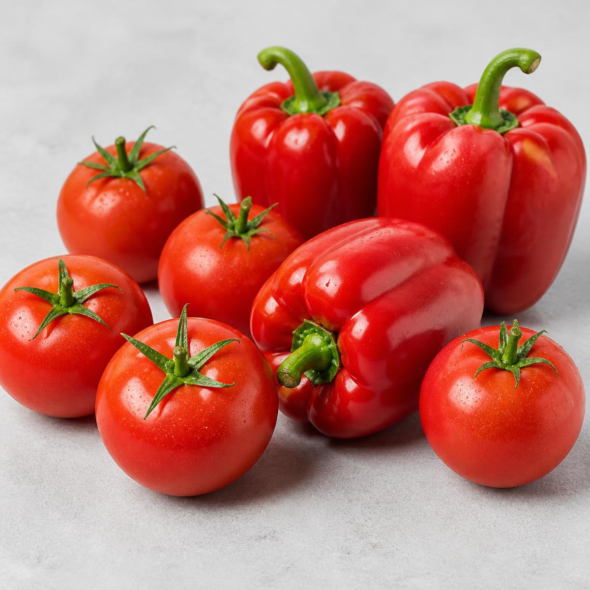 Fresh tomatoes and red peppers on a neutral surface
